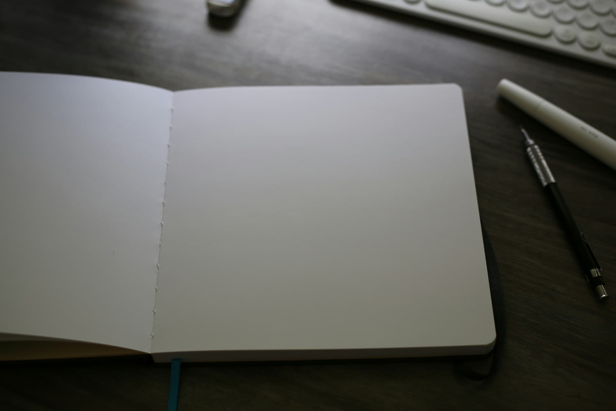 An open notebook beside a keyboard, mid-thought