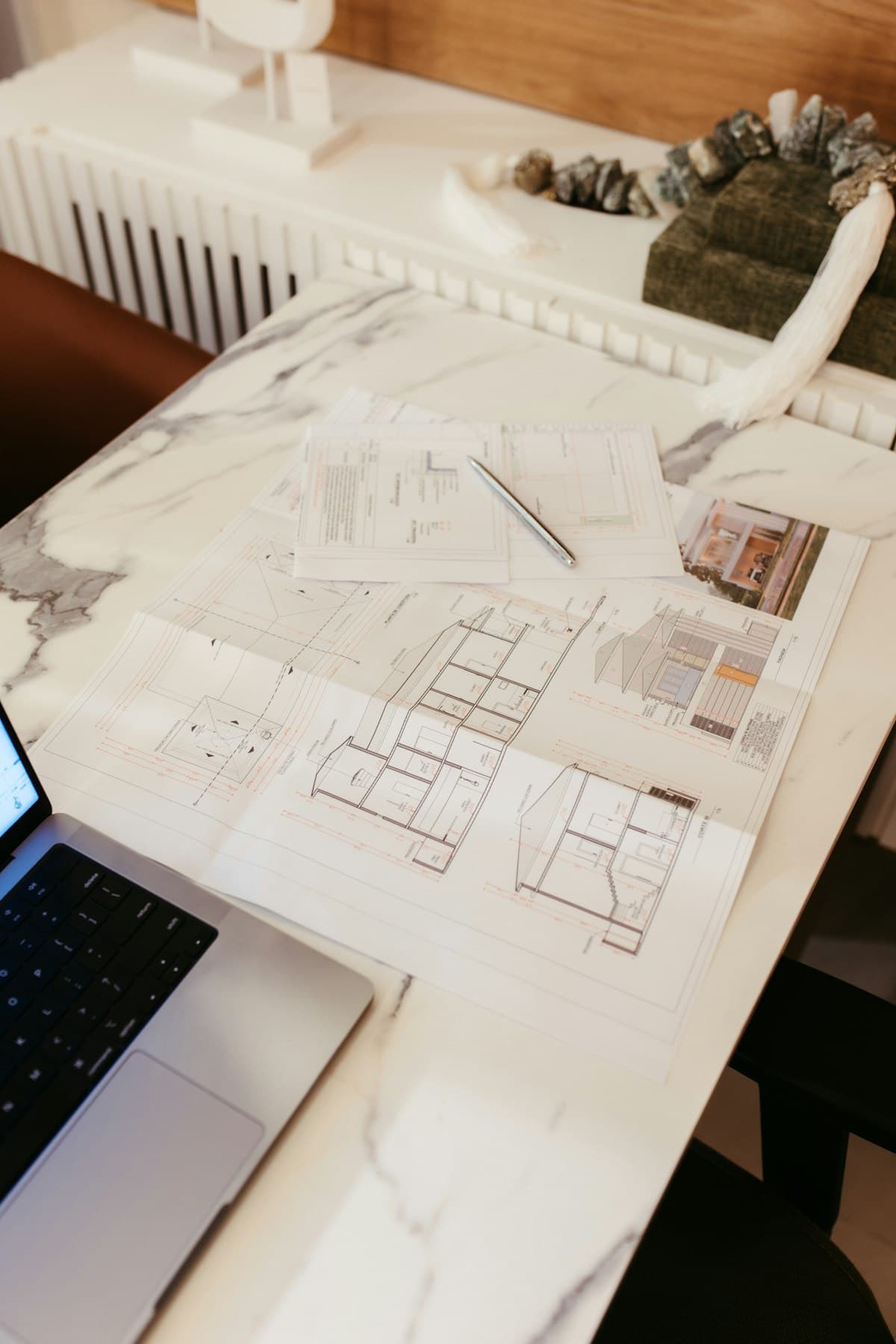 Architectural blueprints and a laptop on a desk